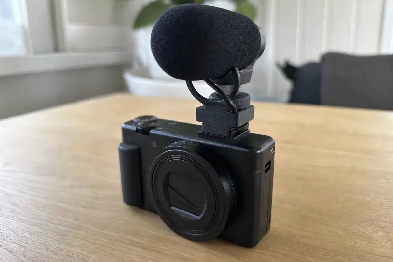 Liten svart 3D-printet adapter med en mikrofon oppå et lite kamera på et skrivebord
