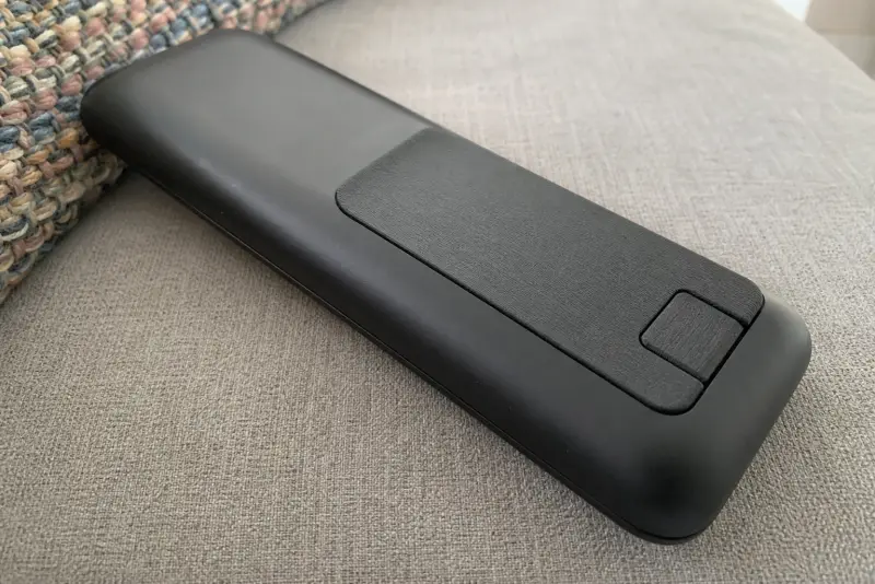 Nytt svart 3D-printet batterilokk bak på en gammel fjernkontroll på en sofa
