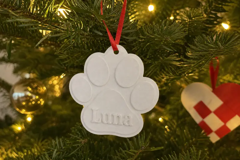 Hvit 3D-printet julepynt formet som en pote med navnet Luna på et juletre
