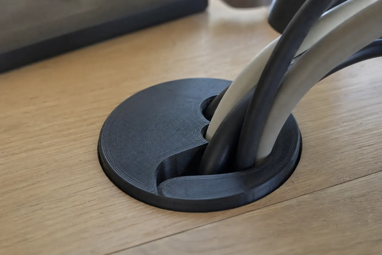 Svart 3D-printet kabelgjennomføring i en pult