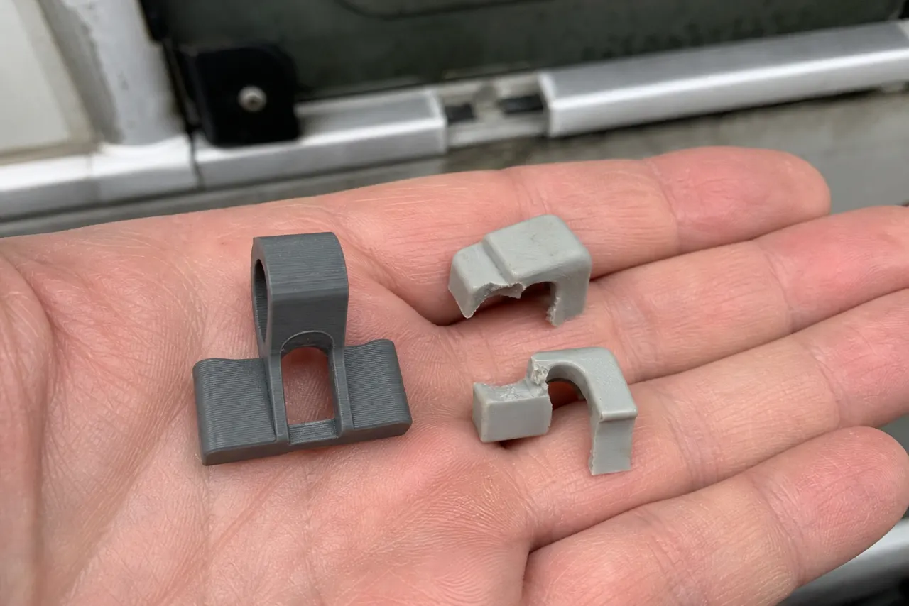 En ny 3D-printet klips holdt ved siden av de to bitene av den gamle