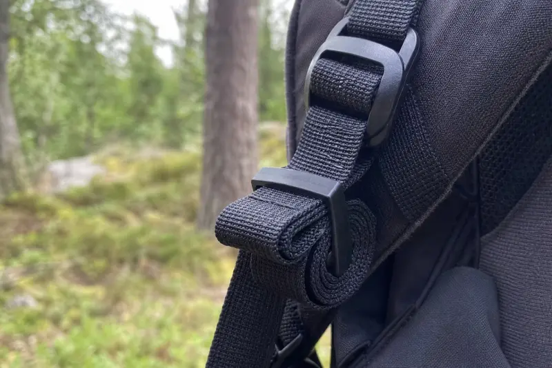 Svart myk 3D-printet holder som samler en opprullet stroppeende på en tursekk
