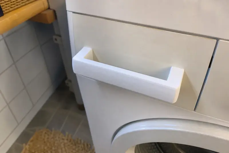 Nytt hvitt 3D-printet håndtak på vaskemiddelskuffen til en eldre vaskemaskin